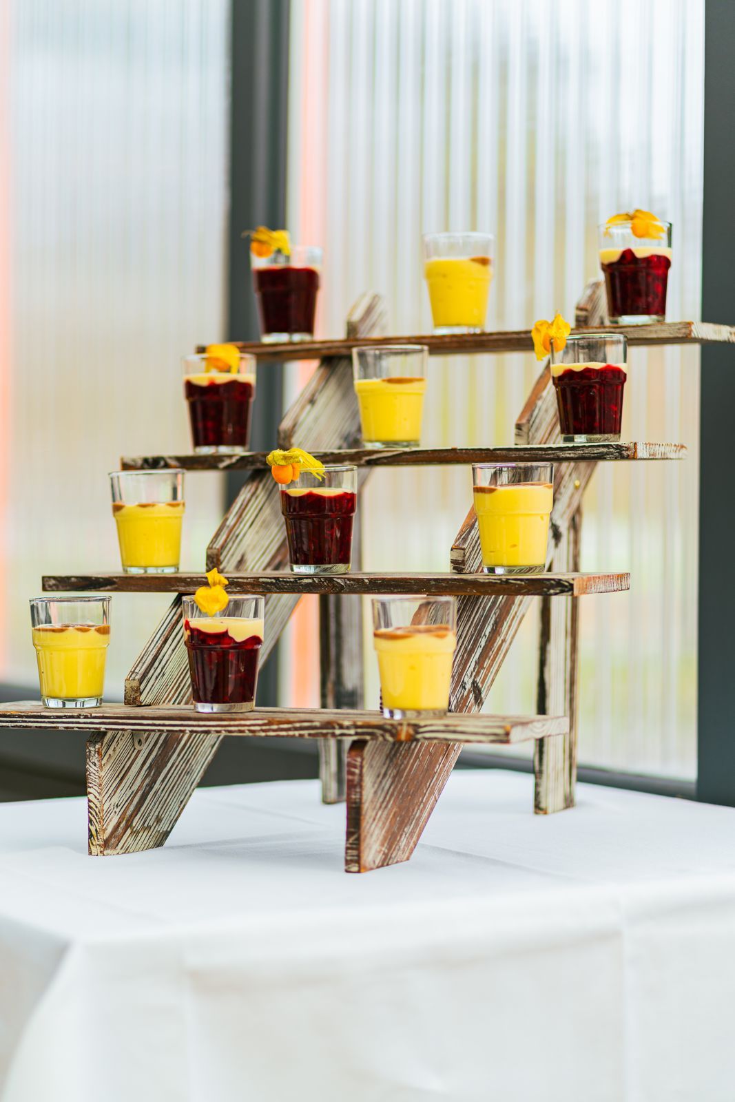 Dessertgläser mit Vanillecreme und roter Grütze auf einer Holzetagere