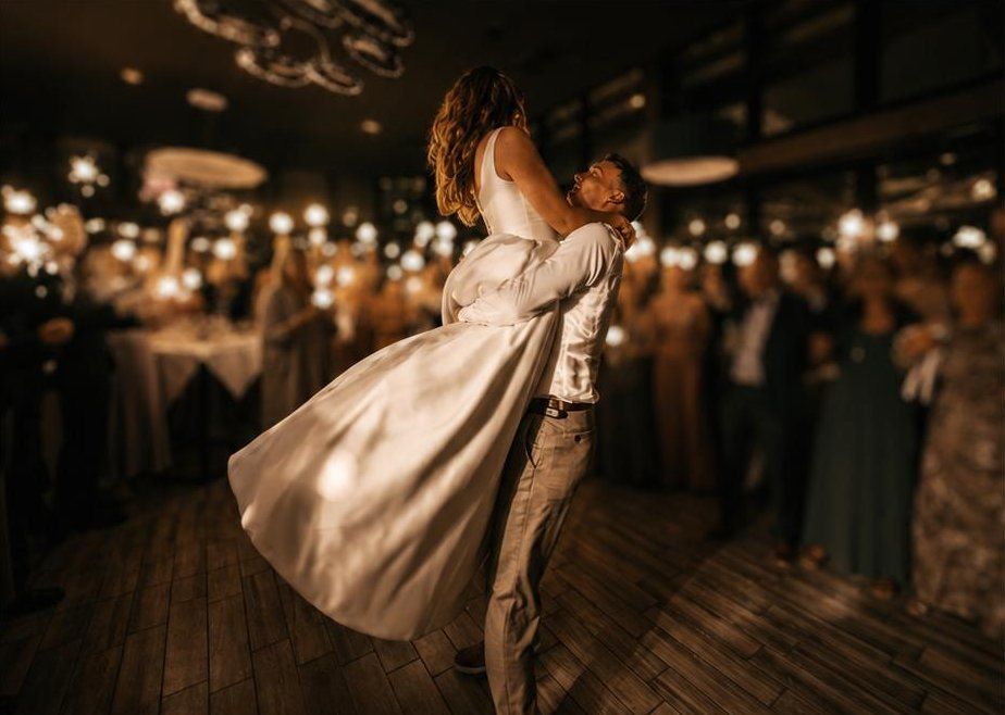 Brautpaar beim Hochzeitstanz im Restaurant, Gäste mit Wunderlichtern im Hintergrund