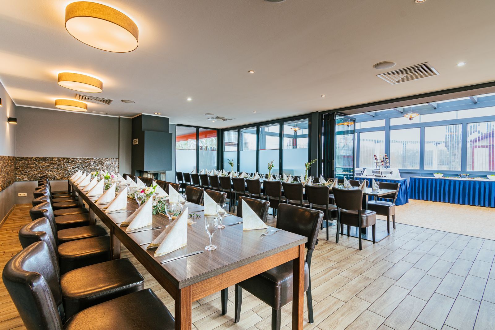 Festlich eingedeckte Tafel im Kaminzimmer des Le Frog, dahinter der Wintergarten mit Buffet