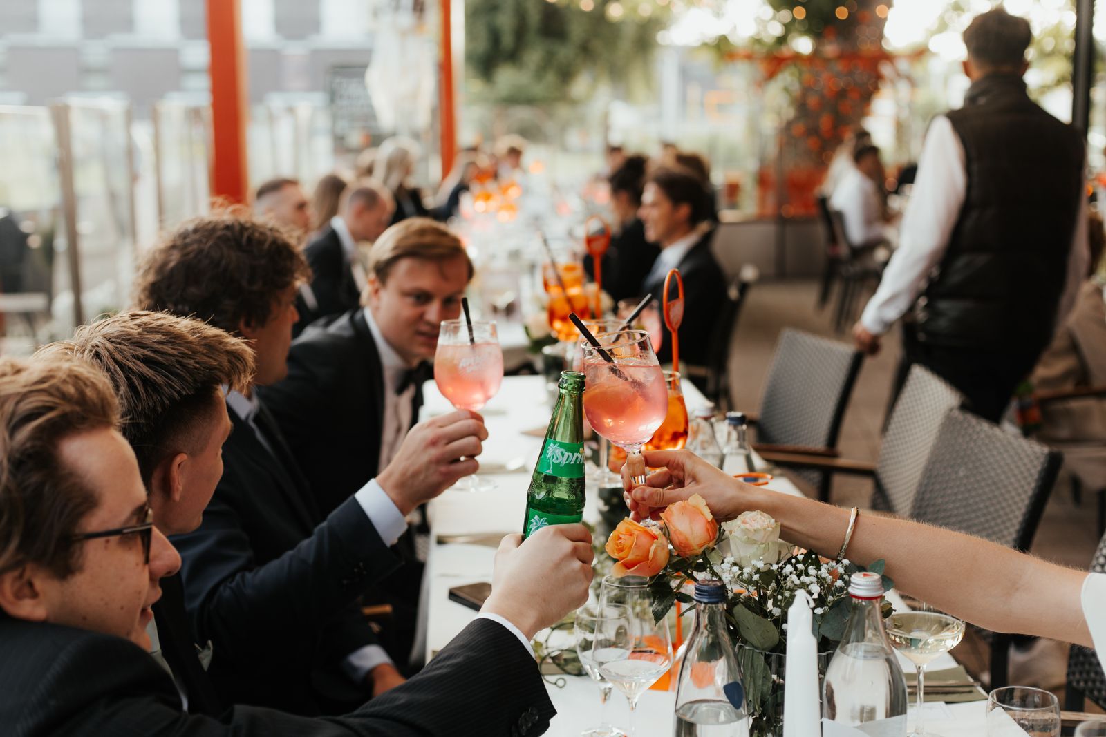 Gäste stoßen an einer langen Tafel auf der Terrasse des Le Frog an